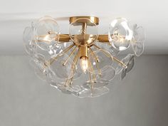 a chandelier hanging from the ceiling with clear glass globes and gold accents