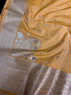 Beautiful Mango Yellow Color Handmade Dupatta with Koniya design and small buttis all over the dupatta, Muted Gold Zari Weaving. Super Light weight and very easy to carry. Can be worn with a Suit or lehenga easily. Please note- : The Color will give a shade of Dark Mango Yellow color in Roomlight and lighter shade of Mango Yellow in Sunlight. Item: DupattaBase color : Mango YellowZari Work : Muted Gold Fabric : Premium quality Banarasi Soft SilkWork : Zari Weaved with tasselsLength of the dupatt Gold Chanderi Sets With Motifs, Gold Sets With Traditional Patterns For Diwali, Traditional Gold Sets For Diwali, Gold Sets With Motifs In Traditional Drape, Gold Sets With Motifs For Diwali, Yellow Banarasi Silk Sets With Zari Weaving, Paithani Silk Sets With Motifs For Puja, Gold Blouse Piece With Motifs For Festive Occasions, Gold Blouse Piece With Motifs For Diwali