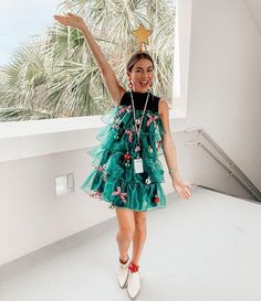 a woman in a green dress is holding her arms up and smiling at the camera