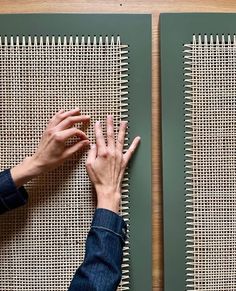 two hands are touching each other's fingers on the wall next to woven panels