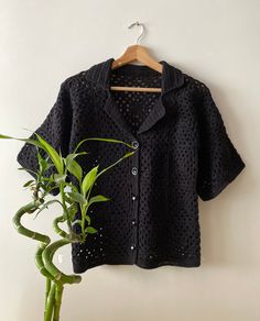 a black jacket hanging on a wall next to a potted plant