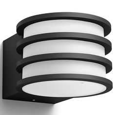 an outdoor light mounted on the side of a wall with four lights in black and white