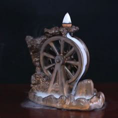 a figurine that is sitting on top of a table with a wheel in front of it