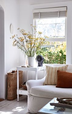 a living room filled with furniture and flowers in vases on top of windowsill