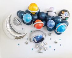 an assortment of balloons and space related items on a white surface with stars around them