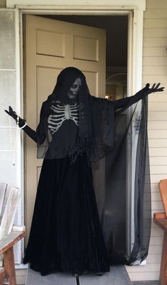 a person in a skeleton costume is standing on the front porch with his arms out