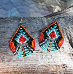 a pair of beaded earrings sitting on top of a piece of wood