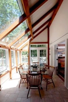 a dining room table and chairs in front of an open window with wooden beams on the ceiling