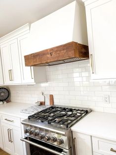 a stove top oven sitting inside of a kitchen next to white cupboards and drawers