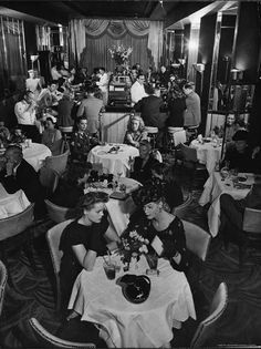 an old black and white photo of people eating in a restaurant