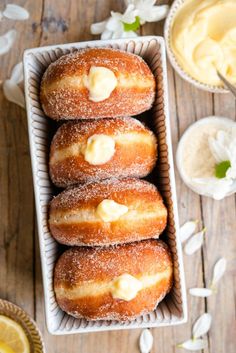 four donuts with icing in a tray next to some lemons and whipped cream