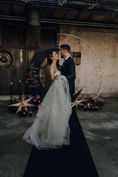 a bride and groom standing in front of a wall with stars on it, surrounded by candles