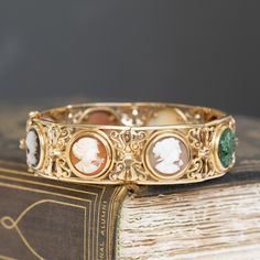 This piece of jewelry comes with it a deep sense of nostalgia! I adore the colors on the different cameos - such a sweet way to add color to one's wrist. But the bets part is the piece's original receipt, dated 1976 from Italy, and its original box. Beautiful an romantic workmanship as only the Italians can! Just beautiful on the wrist. 14kt yellow gold Will fit up to a 7.5" wrist. Please see qualitative report for more information. Luxury Vintage Bracelets For Anniversary, Vintage Gemstone Bracelets For Formal Events, Vintage Gemstone Bracelets For Formal Occasions, Elegant Cameo Bracelet Gift, Intaglio Bangle Jewelry As A Gift, Vintage Gemstone Bracelet For Formal Occasions, Intaglio Bangle Bracelets As A Gift, Vintage Gemstone Bangle For Formal Occasions, Vintage Formal Gemstone Bracelet