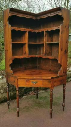 an old wooden bookcase with drawers on the front and bottom, sitting in a driveway