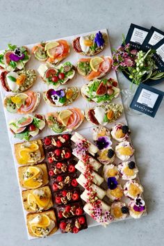 an assortment of appetizers are displayed on a white platter with black tags