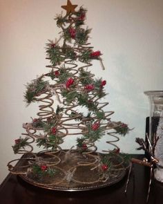 a small christmas tree sitting on top of a wooden table next to a glass jar