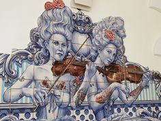 a mural on the side of a building depicting two women playing violin and holding roses