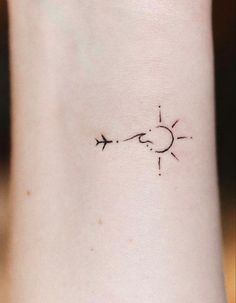 an arrow tattoo on the wrist that is pointing to the sun and moon with two arrows coming out of it