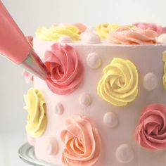 a cake decorated with pink, yellow and orange frosting roses on a silver platter