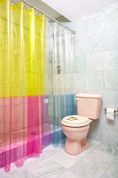 a pink toilet sitting next to a colorful shower curtain