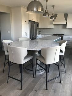 a kitchen with an island table and chairs in the center, surrounded by white cabinets