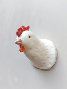 a white rooster figurine sitting on top of a table next to a wall