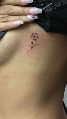 a woman's stomach with a small flower tattoo on her left side ribcage