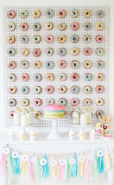 a table topped with lots of donuts next to a wall covered in doughnuts