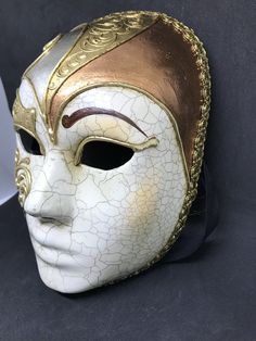 "Size: one size Traditional and original papier-mache Venetian mask, handmade and decorated with three leaf,gold,silver and bronze, cracked technique, stucco and acrylics. This traditional Venetian mask shape is called \"Volto mask\" and is a full face mask. All our masks are handmade papier-machè masks, made in Venice. Our decorators use techniques typical of the Venetian tradition such as stucco, acrylics, gold and silver-leaf, macramè, passementerie, pearls and crequelè to give you a wide ran Traditional Gold Masks And Prosthetics For Costume, Traditional Gold Masks And Prosthetics For Festivals, Traditional Gold Costume Masks And Prosthetics, Traditional Gold Masks And Prosthetics For Carnival, Changeling Wizard, White Venetian Masks And Prosthetics For Festivals, Artistic Gold Masks And Prosthetics For Costume, Traditional White Masks For Masquerade, Artistic White Masks For Festivals