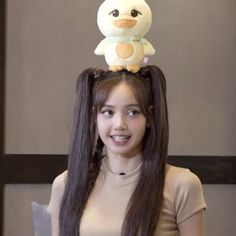 a girl with long hair and a stuffed animal on top of her head