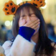 a young woman covers her face while wearing animal ears