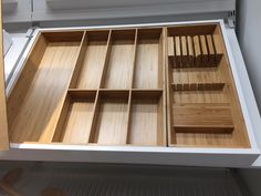 an open drawer with wooden dividers in it