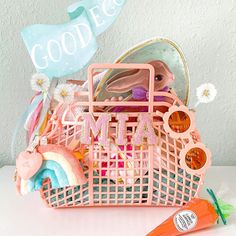 a pink shopping basket filled with lots of toys and candy sitting on top of a table