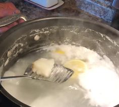 two eggs are being cooked in a pot with boiling water and butter on the side