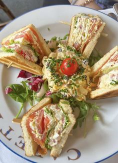 a white plate topped with sandwiches on top of a blue and white table cloths