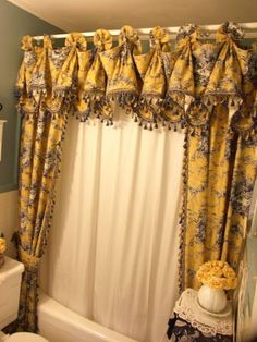 a bath room with a toilet a sink and a shower curtain covered in yellow flowers