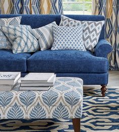 a blue couch sitting in front of a window next to a table with books on it