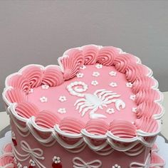 a heart shaped cake with pink frosting and white decorations