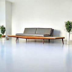 a couch sitting on top of a white floor next to two potted plantes