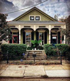 an old house with a fountain in front of it on a street corner near a fence