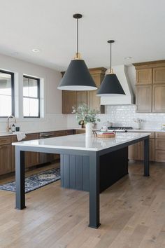 a large kitchen with two pendant lights hanging from the ceiling and an island in the middle