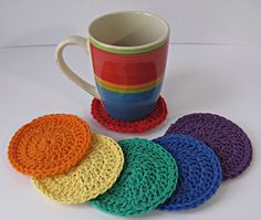 four crocheted coasters are next to a coffee cup