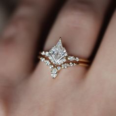 a woman's hand with a diamond ring on top of her finger and an engagement band