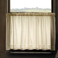 an open window with white curtains and a plaid umbrella