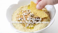 a white bowl filled with food on top of a wooden table and the words fire roasted hatch chile hummus