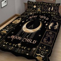 a bed with a black comforter that has the moon and stars on it