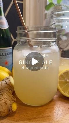 a glass jar filled with liquid next to lemons and ginger