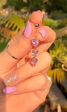 a woman's hand with pink manicures and rings on her fingers, holding a ring