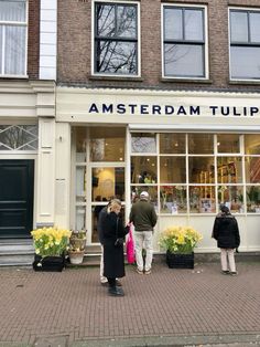 people are standing in front of an amsterdam tulip shop