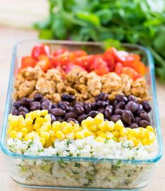 a colorful salad in a glass dish with lettuce, tomatoes and black beans